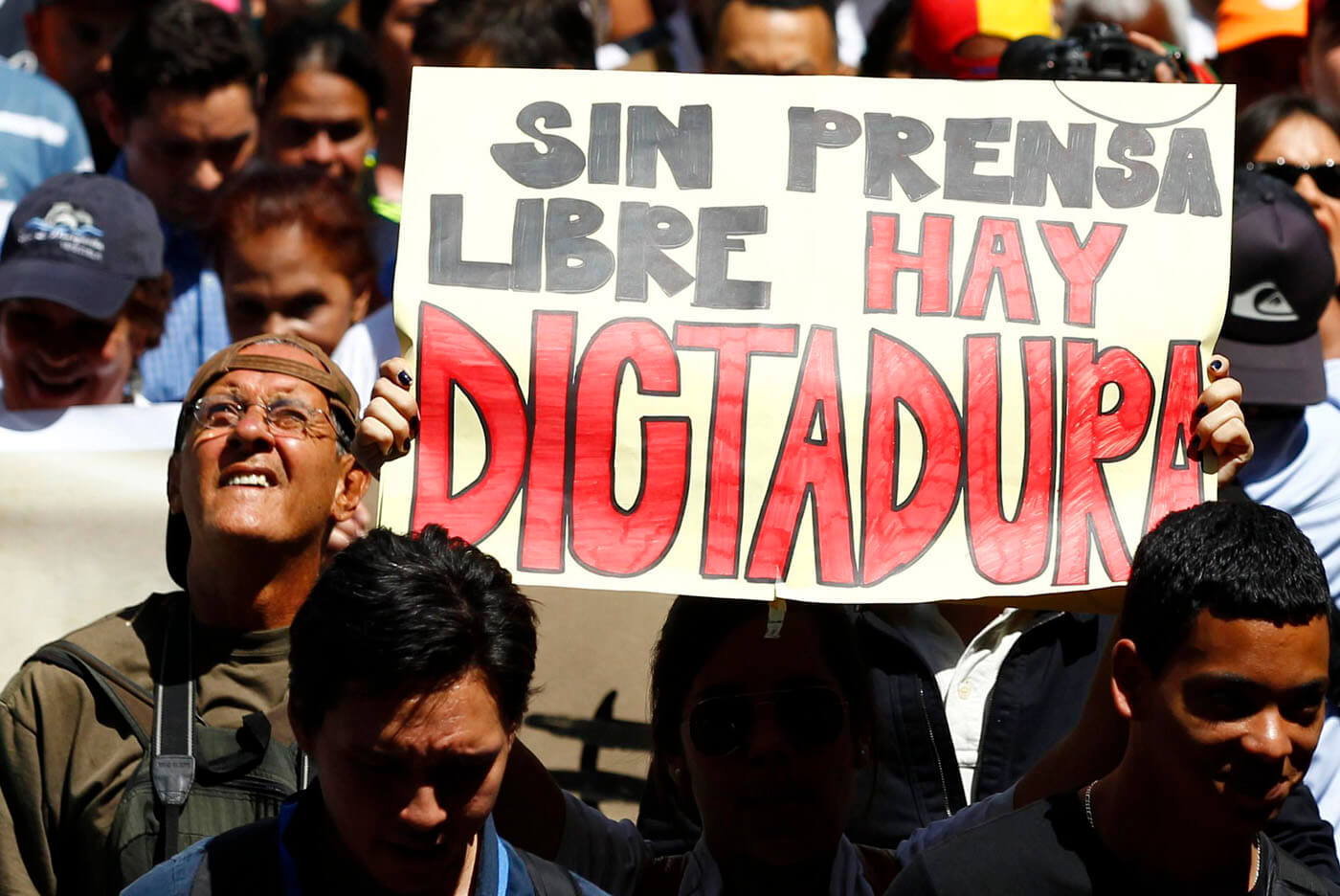 A woman holds up a sign reading "'Without free press, there is a dictatorship", during a protest by newspaper workers and opposition parties to demand from the government U.S. dollars at a prime rate to buy paper for their publications, in Caracas February 11, 2014. Newspaper owners claim they are close to running out of their stock of paper due to the lack of dollars to import it, local media said. REUTERS/Carlos Garcia Rawlins (VENEZUELA - Tags: POLITICS CIVIL UNREST MEDIA BUSINESS)